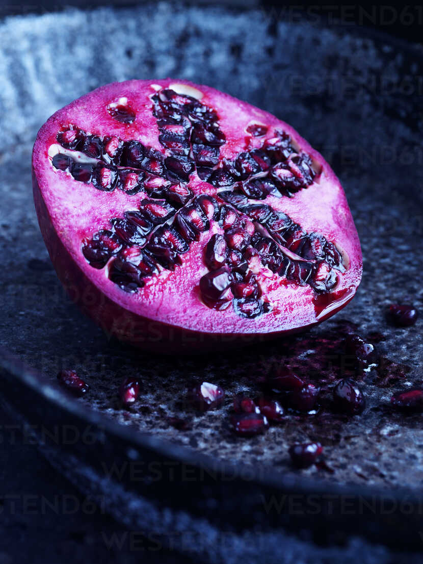 Half a pomegranate on blue plate stock photo