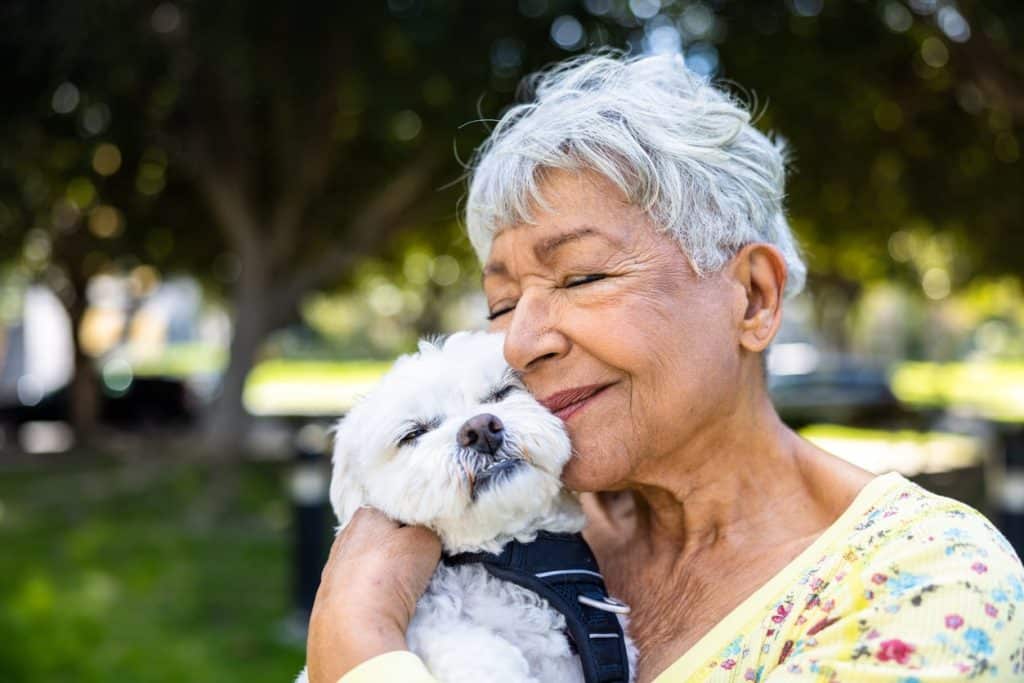 An old woman cuddling with her happy dog