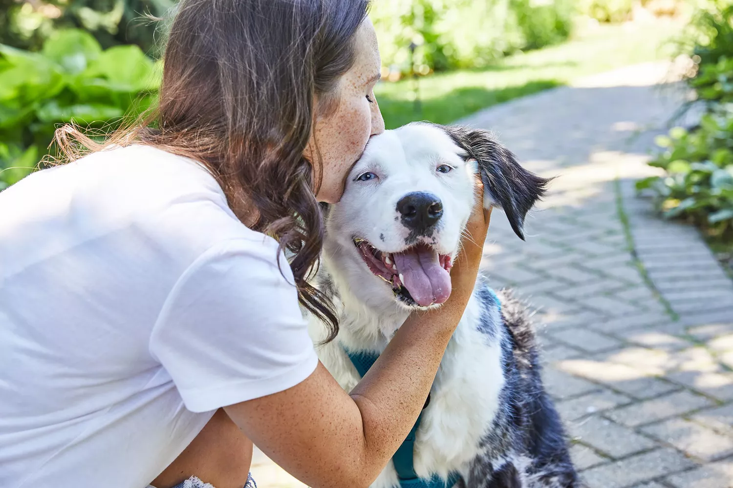 woman kissing dog on head